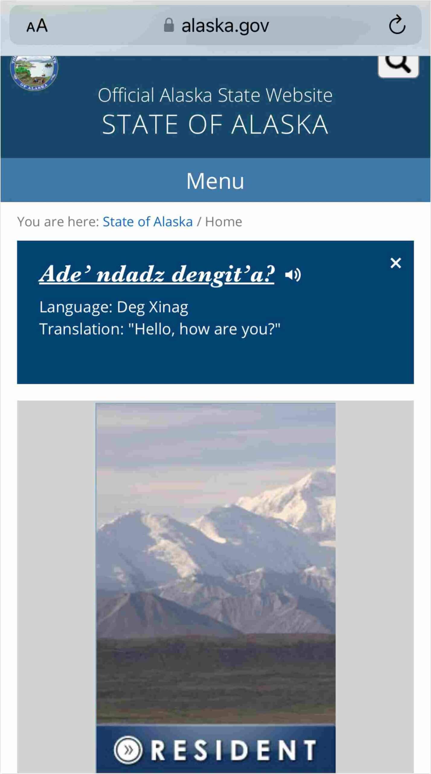Mobile screenshot of the Alaska State Website arranged in a single-column layout. At the top, there's the state's seal followed by the site’s title. A greeting in Deg Xinag and its English translation are prominently displayed. Below, a scenic view of Alaskan mountains is visible, leading to a navigation bar for 'RESIDENT' suggesting further content below.