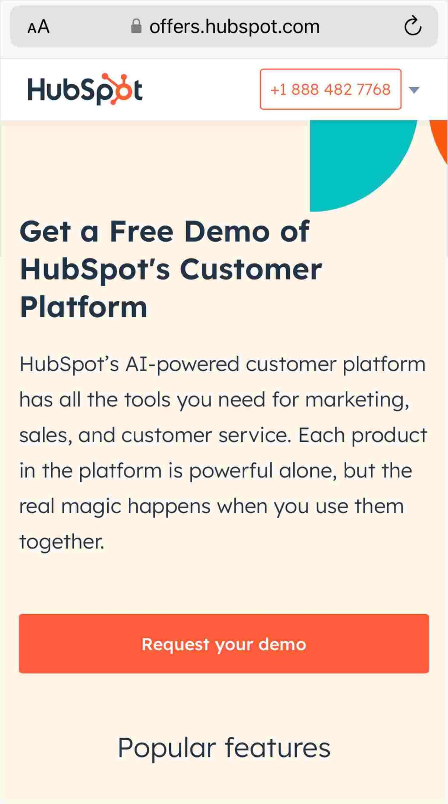 Screenshot of a mobile landing page from HubSpot featuring a header with their logo and a phone number. Below is a prominent heading stating 'Get a Free Demo of HubSpot’s Customer Platform.' A paragraph explains HubSpot’s AI-powered customer platform encompassing tools for marketing, sales, and customer service, noting the synergy when using the products together. A large, attention-grabbing red button reads 'Request your demo,' indicating a call-to-action. The section below the button is titled 'Popular features,' indicating more information is available if scrolled.