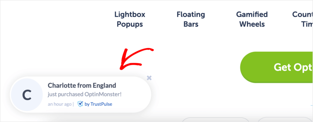 TrustPulse notification on OptinMonster's website. It says "Charlotte from England just purchased OptinMonster!" Smaller, gray text says "an hour ago."