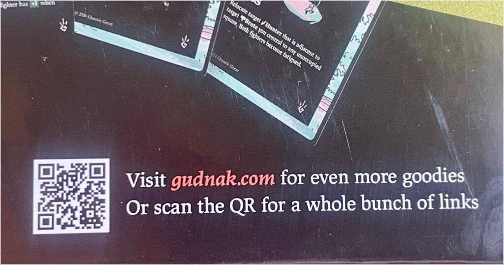 QR code mobile marketing example from Gudnak. On the back of a game box, there's a QR code with the words "Visit gudnak.com for even more goodies. Or scan the QR for a whole bunch of links."